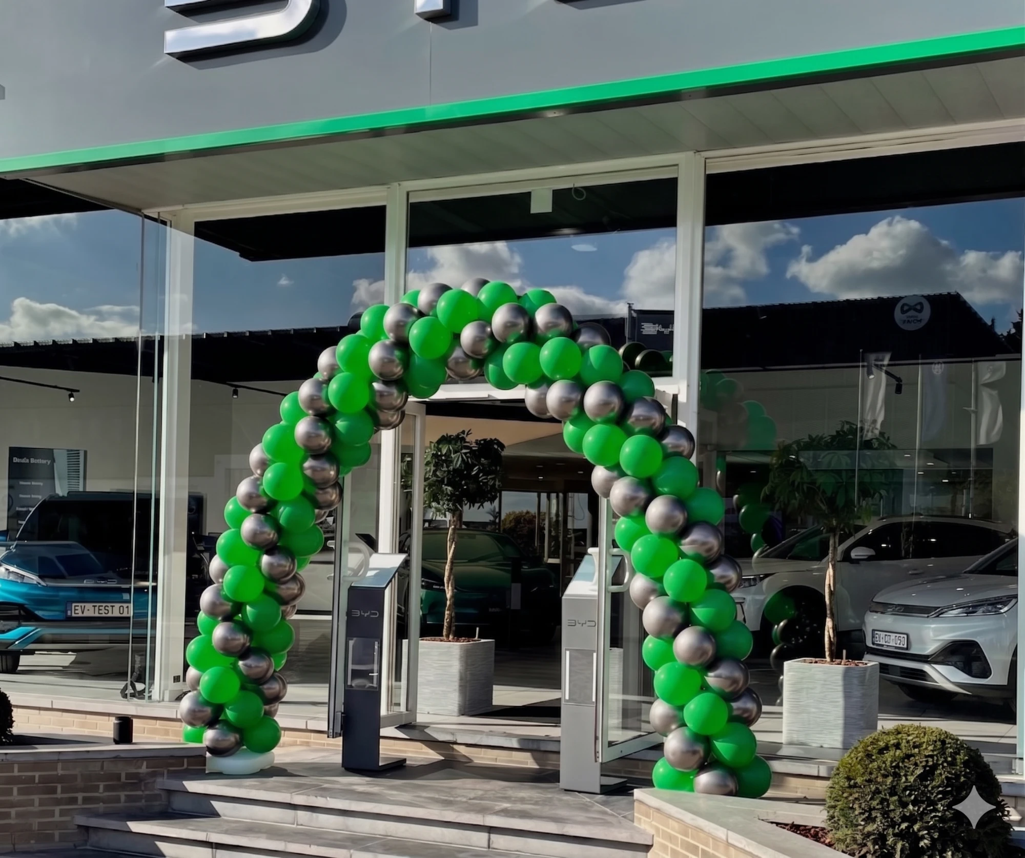 Arche en ballons vert et argent devant showroom BYD · Ballons déco · Décoration événement automobile